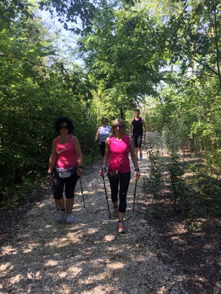 Due camminatrici con i bastoncini su un sentiero tra gli alberi